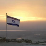 Drapeau d'Israël en premier plan avec couché de soleil en fond