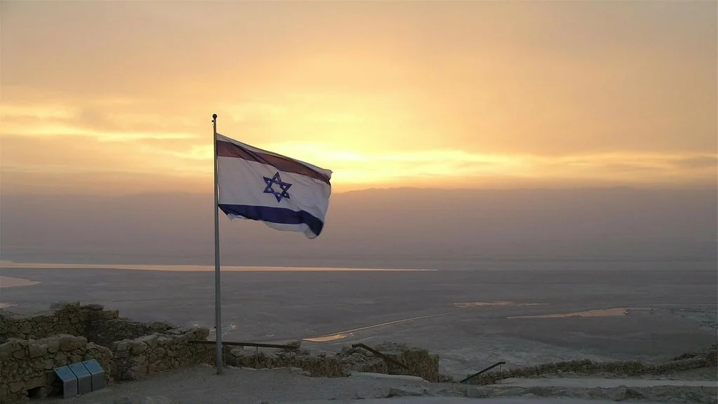 Drapeau d'Israël en premier plan avec couché de soleil en fond